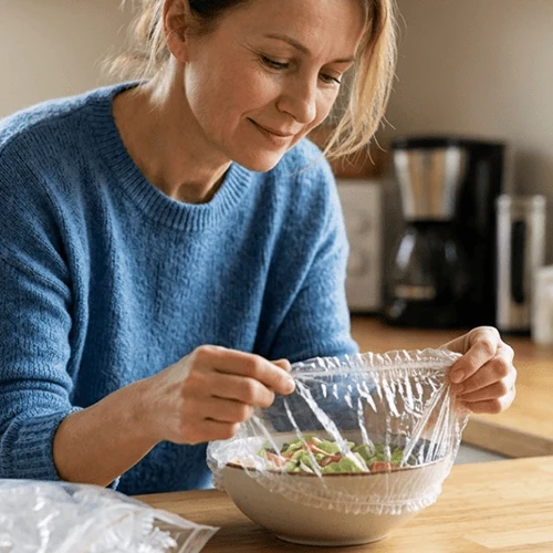 Woman stretching a transparent elastic food cover over a bowl